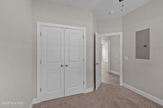 unfurnished bedroom featuring carpet floors, baseboards, electric panel, and a closet