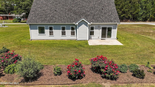 back of house featuring a lawn, a patio, and roof with shingles