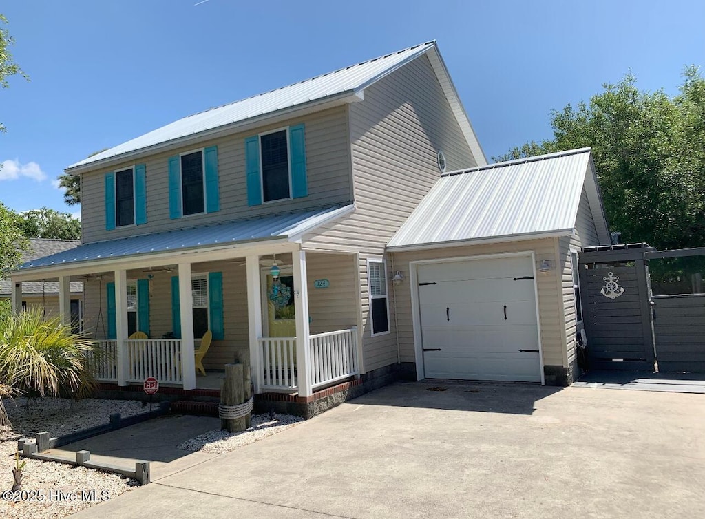 view of front of house with a garage, covered porch, driveway, and metal roof