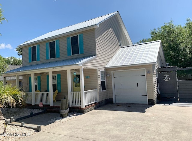 view of front of house with a garage, covered porch, driveway, and metal roof