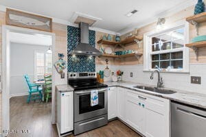 124 NE 15th St, Oak Island, NC 28465 - kitchen featuring a sink, open shelves, wall chimney exhaust hood, backsplash, and appliances with stainless steel finishes