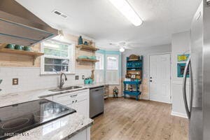 124 NE 15th St, Oak Island, NC 28465 - kitchen with a sink, stainless steel appliances, open shelves, and light wood-style floors