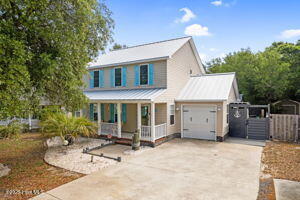 124 NE 15th St, Oak Island, NC 28465 - farmhouse-style home with driveway, fence, metal roof, a garage, and a porch