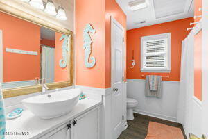 124 NE 15th St, Oak Island, NC 28465 - full bathroom with toilet, vanity, a wainscoted wall, and wood finished floors