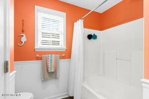 124 NE 15th St, Oak Island, NC 28465 - bathroom featuring toilet, shower / bath combo, and a wainscoted wall