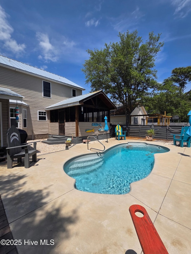 view of swimming pool featuring a sunroom, a patio area, fence, and a fenced in pool