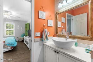 124 NE 15th St, Oak Island, NC 28465 - bathroom with vanity, connected bathroom, a ceiling fan, and wood finished floors