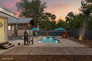 124 NE 15th St, Oak Island, NC 28465 - pool at dusk featuring entry steps, a patio, a fenced in pool, and a fenced backyard