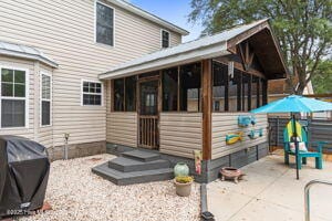 124 NE 15th St, Oak Island, NC 28465 - rear view of house featuring a sunroom and a patio area