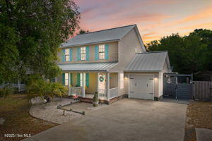 124 NE 15th St, Oak Island, NC 28465 - view of front of property featuring a porch, a garage, metal roof, and driveway