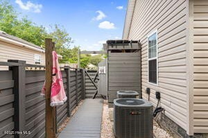 124 NE 15th St, Oak Island, NC 28465 - view of property exterior featuring cooling unit and fence