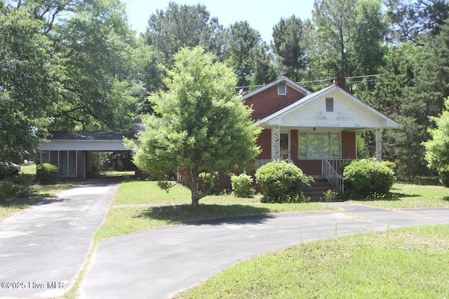 view of front of property featuring a front lawn, a porch, brick siding, and aphalt driveway