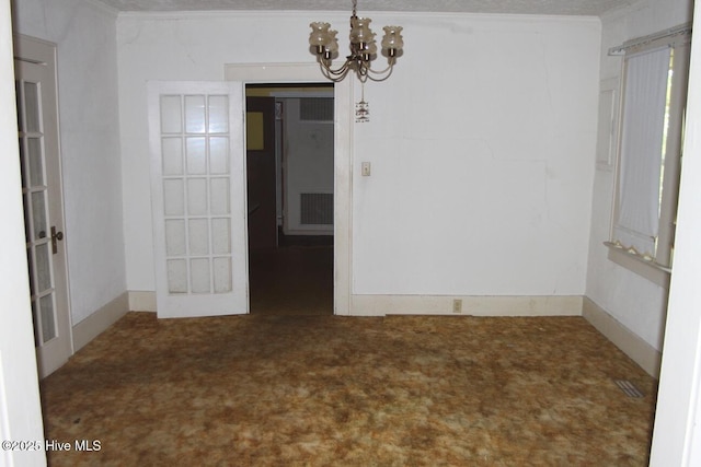 carpeted empty room featuring a notable chandelier and french doors