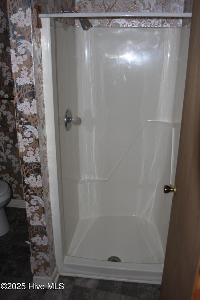 full bathroom with baseboards, a stall shower, and toilet
