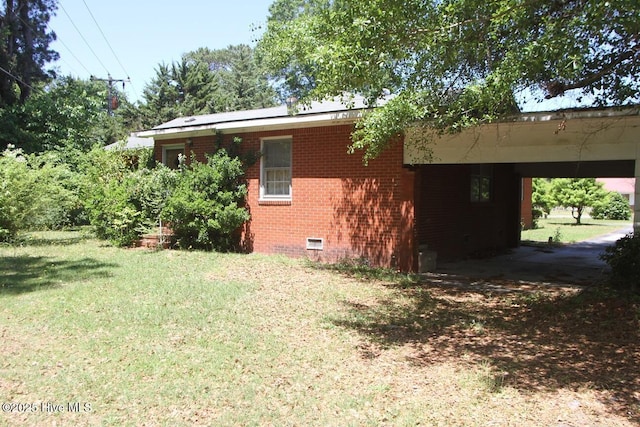 view of side of home with a lawn, an attached carport, brick siding, and crawl space