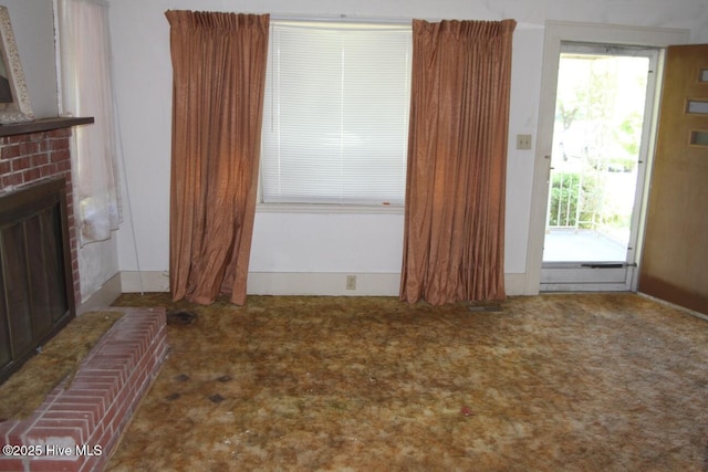 unfurnished living room featuring plenty of natural light, carpet, and a brick fireplace