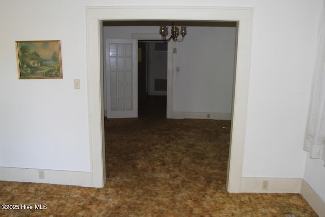 hall featuring an inviting chandelier and carpet