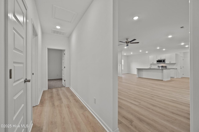 hallway featuring recessed lighting, visible vents, baseboards, and light wood-type flooring
