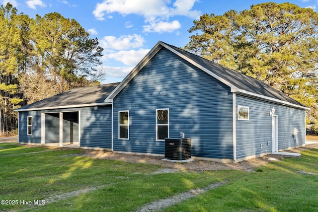 rear view of house with cooling unit and a lawn