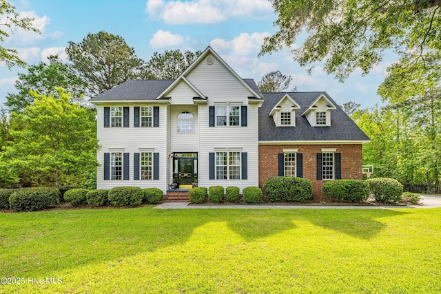 view of front of house featuring a front lawn, a shingled roof, and brick siding