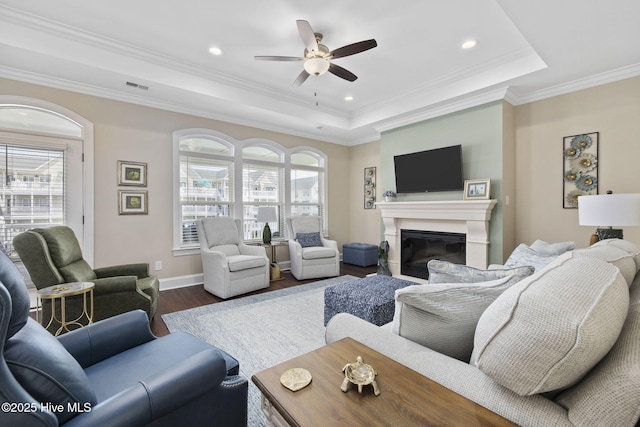 living room with a healthy amount of sunlight, a tray ceiling, visible vents, and dark wood-style floors
