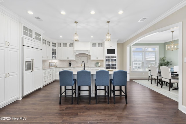 kitchen with stainless steel double oven, paneled built in refrigerator, white cabinetry, light countertops, and arched walkways