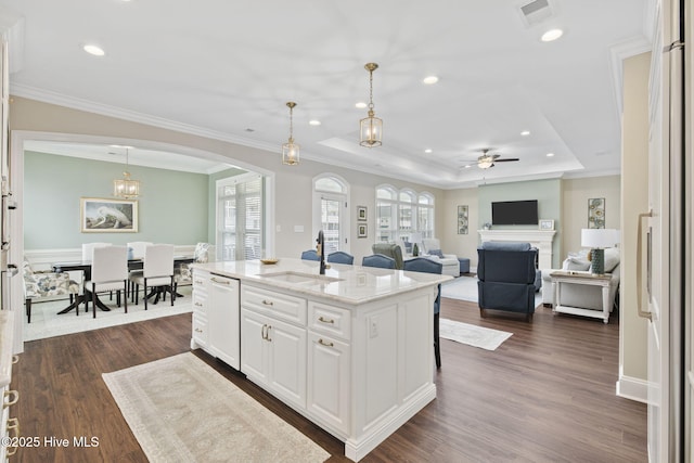 kitchen featuring a sink, a raised ceiling, visible vents, arched walkways, and dishwasher