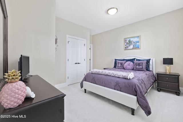 bedroom with a closet, light colored carpet, and baseboards
