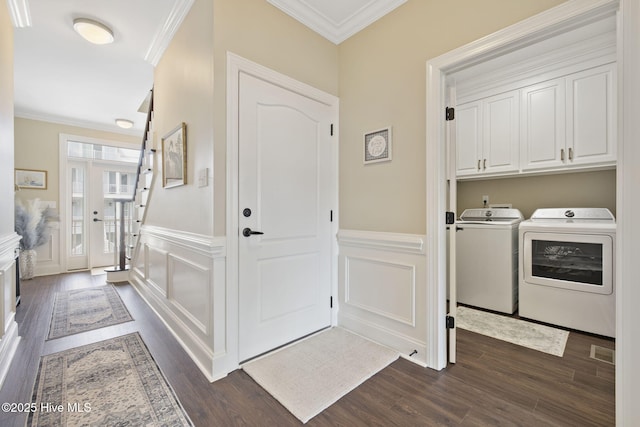 laundry room featuring ornamental molding, washer and dryer, a decorative wall, and dark wood finished floors