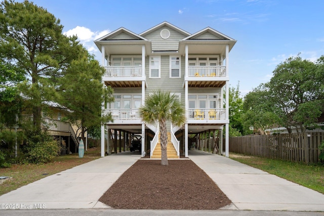 beach home with driveway, stairs, a carport, and a balcony