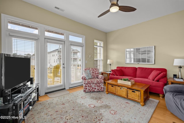 living area with wood finished floors, visible vents, and a ceiling fan