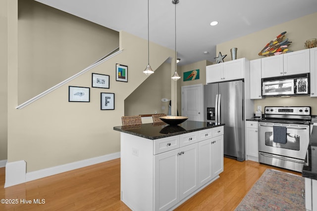 kitchen featuring light wood-type flooring, decorative light fixtures, white cabinetry, a kitchen island, and appliances with stainless steel finishes