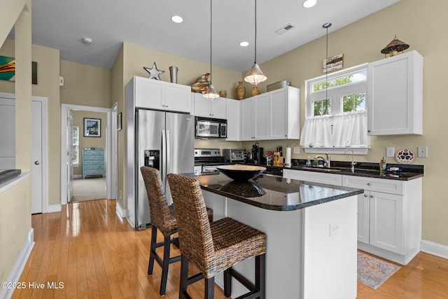 kitchen with a breakfast bar, visible vents, white cabinetry, baseboards, and appliances with stainless steel finishes