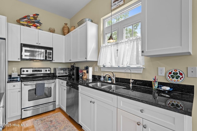 kitchen featuring white cabinets, stainless steel appliances, light wood finished floors, and a sink