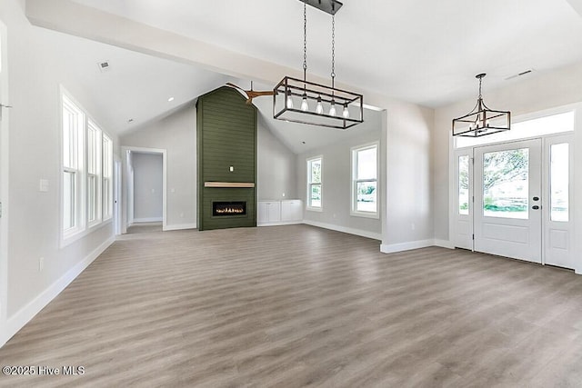 1104 Soundside Rd, Edenton, NC 27932 - unfurnished living room featuring wood finished floors, high vaulted ceiling, a chandelier, a large fireplace, and baseboards