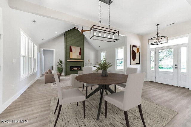 1104 Soundside Rd, Edenton, NC 27932 - dining space featuring lofted ceiling, a fireplace, light wood finished floors, an inviting chandelier, and baseboards