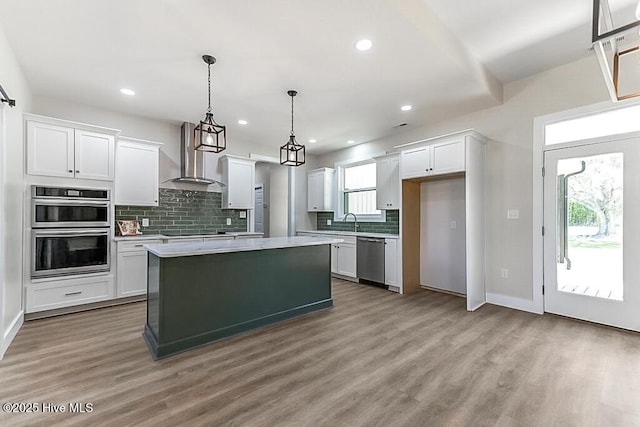 1104 Soundside Rd, Edenton, NC 27932 - kitchen with wall chimney exhaust hood, light wood-type flooring, white cabinetry, backsplash, and appliances with stainless steel finishes