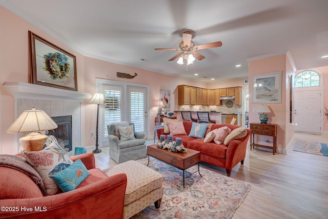 1105 Avebury Ct, Leland, NC 28479 - living room featuring crown molding, a tiled fireplace, a ceiling fan, baseboards, and light wood-type flooring