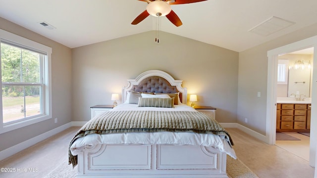 bedroom with ensuite bathroom, light colored carpet, visible vents, vaulted ceiling, and baseboards
