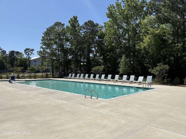 community pool with a patio area and fence