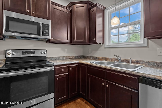 110 Costa Ct, Sneads Ferry, NC 28460 - kitchen featuring appliances with stainless steel finishes, a sink, dark brown cabinetry, decorative light fixtures, and dark wood-type flooring