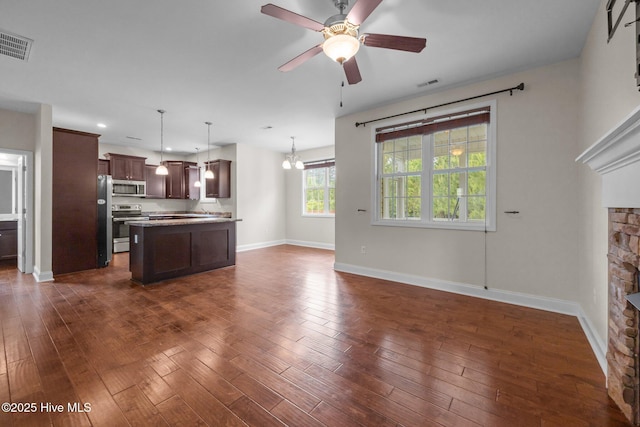 110 Costa Ct, Sneads Ferry, NC 28460 - unfurnished living room featuring a ceiling fan, a stone fireplace, baseboards, dark wood-type flooring, and a chandelier