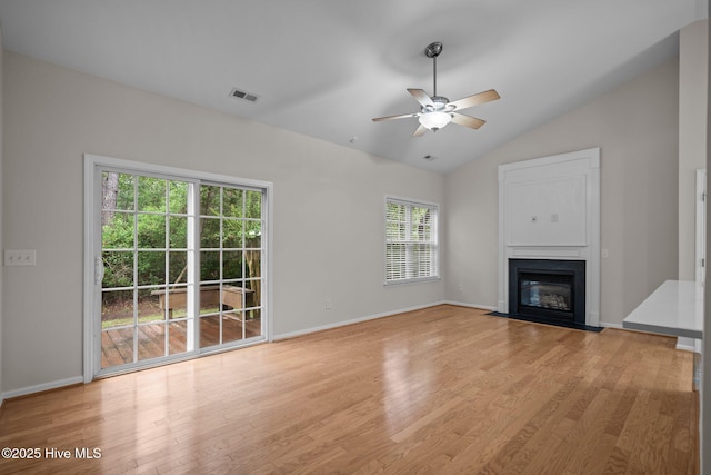 unfurnished living room featuring a fireplace with flush hearth, light wood-style floors, a ceiling fan, vaulted ceiling, and baseboards