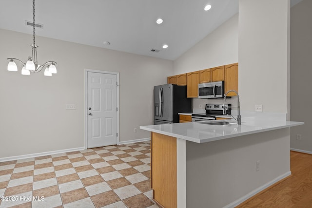 kitchen with appliances with stainless steel finishes, a chandelier, a sink, light countertops, and hanging light fixtures