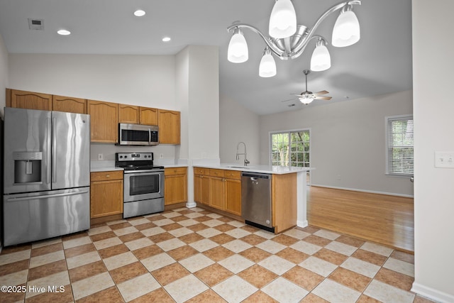 kitchen featuring stainless steel appliances, a peninsula, light countertops, ceiling fan, and high vaulted ceiling