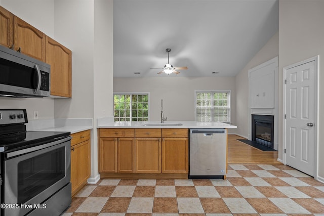 kitchen with appliances with stainless steel finishes, a sink, a peninsula, light countertops, and ceiling fan