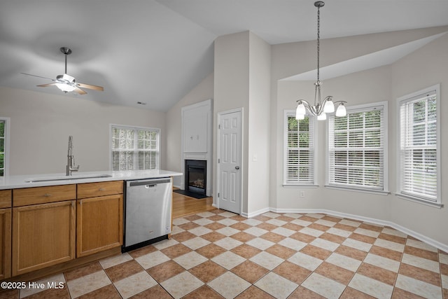 kitchen featuring dishwasher, a sink, light countertops, vaulted ceiling, and a fireplace with flush hearth