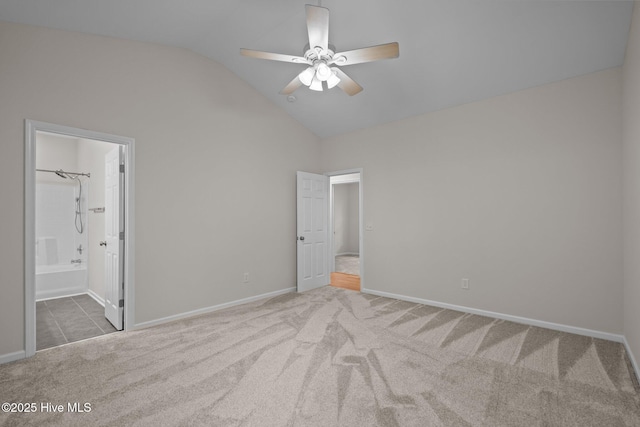 unfurnished bedroom with vaulted ceiling, carpet flooring, baseboards, ensuite bath, and a ceiling fan