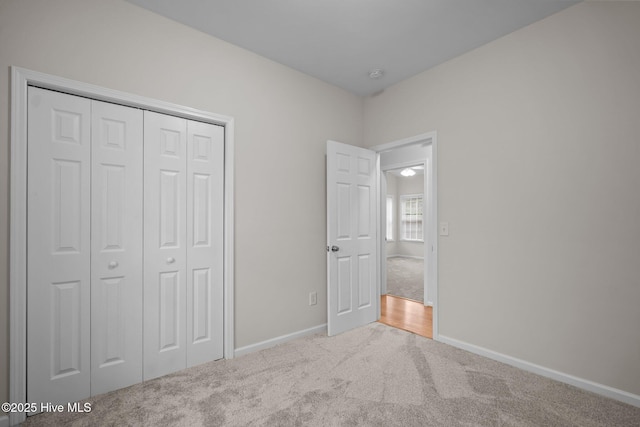 unfurnished bedroom featuring carpet flooring, baseboards, and a closet