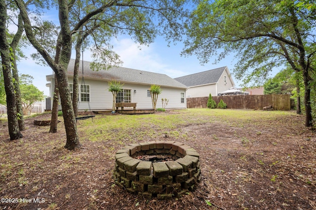 rear view of property with an outdoor fire pit, fence, and a deck